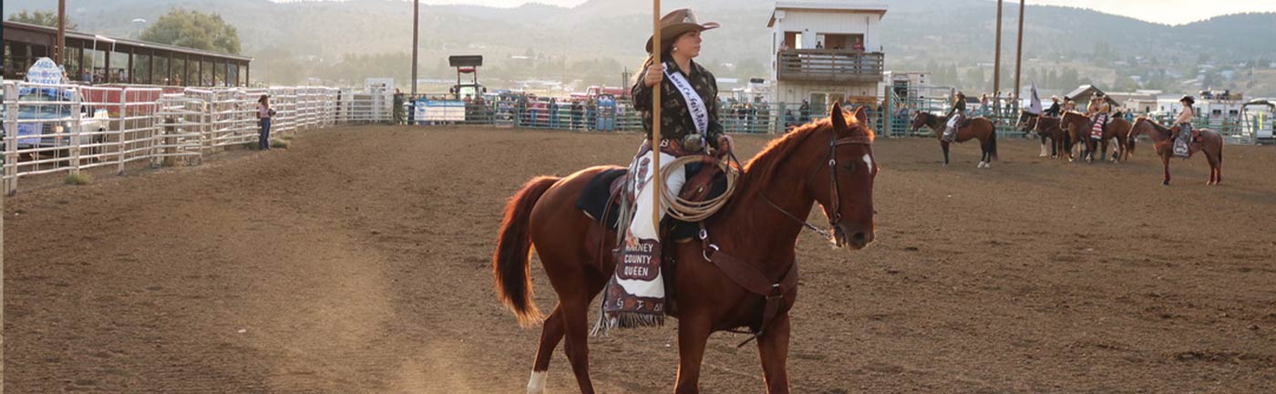 woman on horseback holding a flag in a rodeo arena